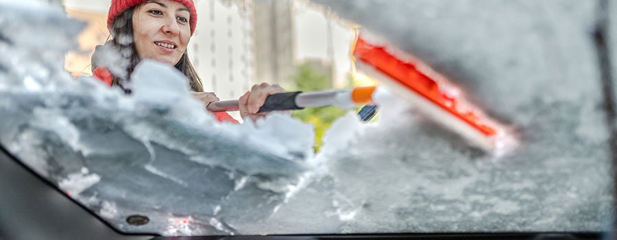 Women scrapping snow ice off car window