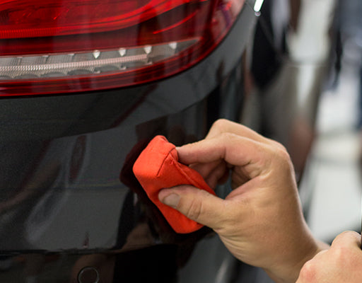 Hand wiping down bumper of car-ceramic coating