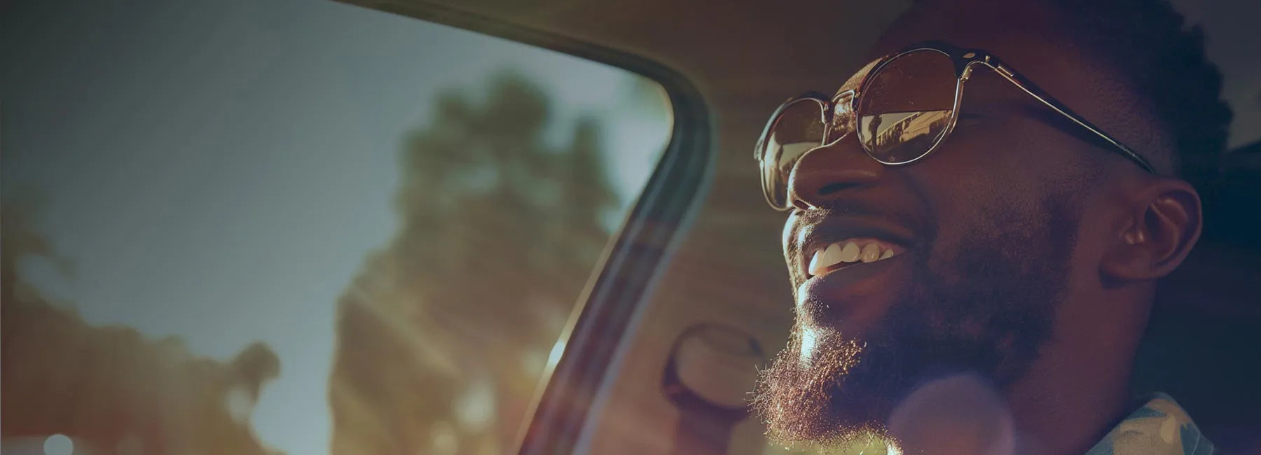 Smiling guy  wearing sunglasses with sun rays shining into Car 